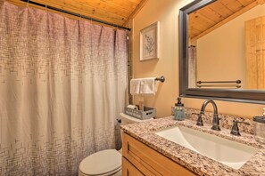 A bathroom with a shower curtain, toilet, sink, and mirror. - Secluded Leesburg Retreat w/ Private Hot Tub! (Leesburg)