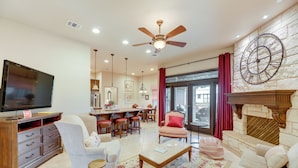A spacious living room with a television, comfortable seating, a fireplace, and a kitchen area in the background. - Pool & Hot Tub in Sunny Smithville Getaway! (Smithville)