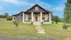 A two-story house with a stone facade, a front porch with columns, and a pathway leading to the entrance. - Pool & Hot Tub in Sunny Smithville Getaway! (Smithville)
