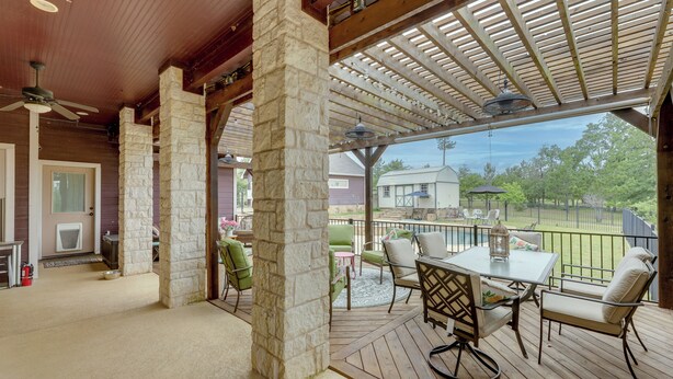 A covered patio with stone pillars, a glass table, and outdoor furniture. - Pool & Hot Tub in Sunny Smithville Getaway! (Smithville)
