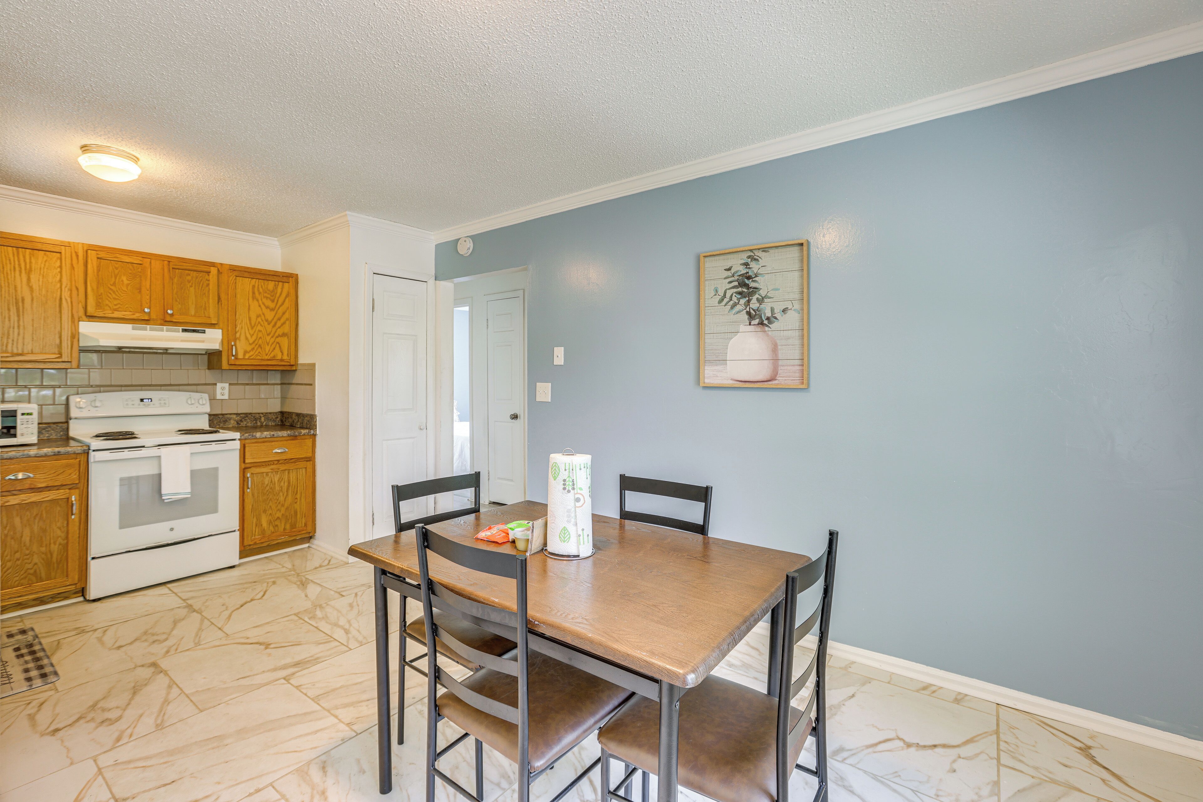A kitchen with wooden cabinets, a white stove, and a dining table with chairs.