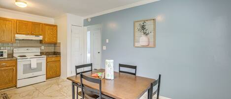 A kitchen with wooden cabinets, a white stove, and a dining table with chairs.