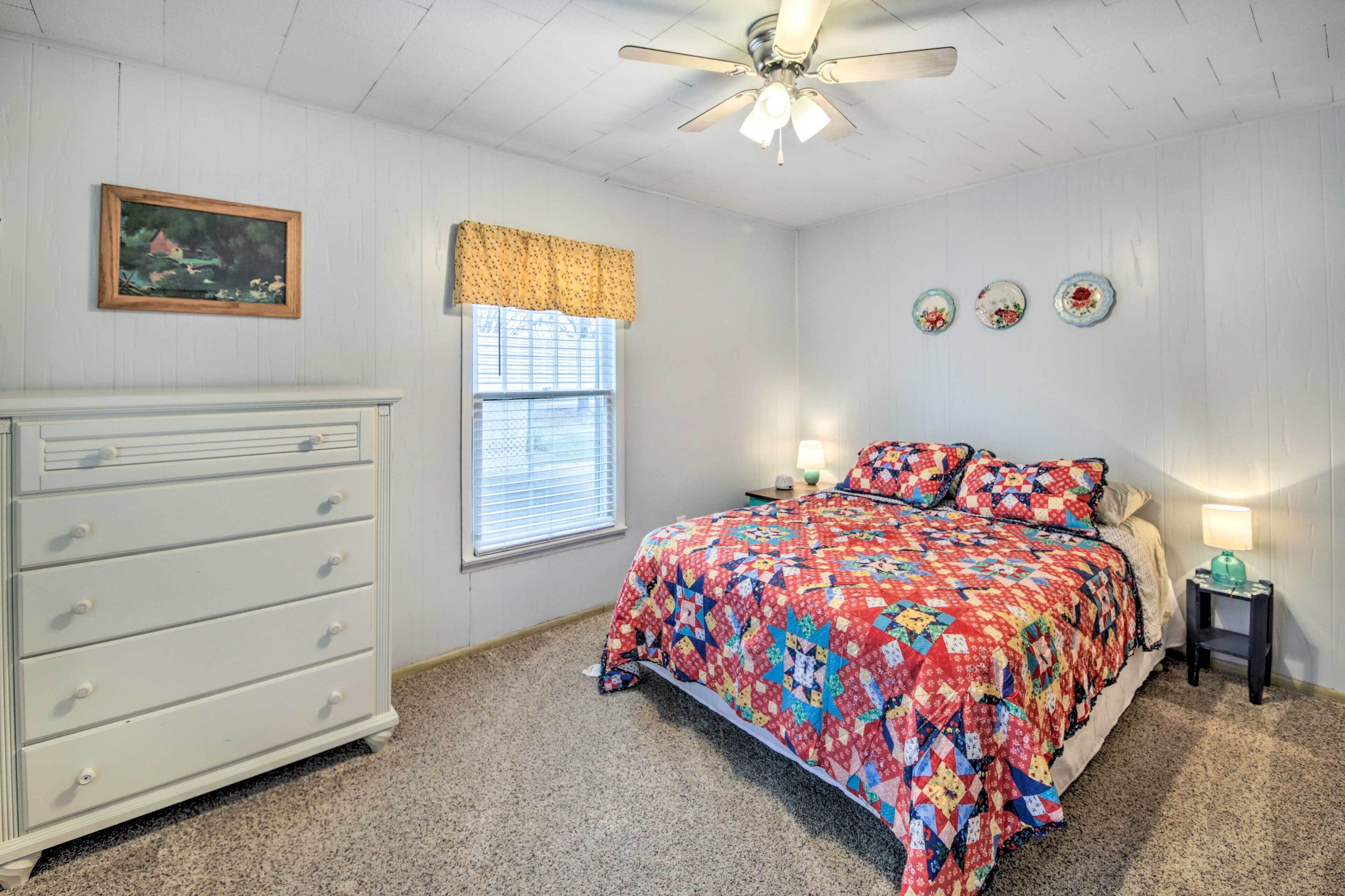A bedroom with a bed, dresser, window, and ceiling fan.