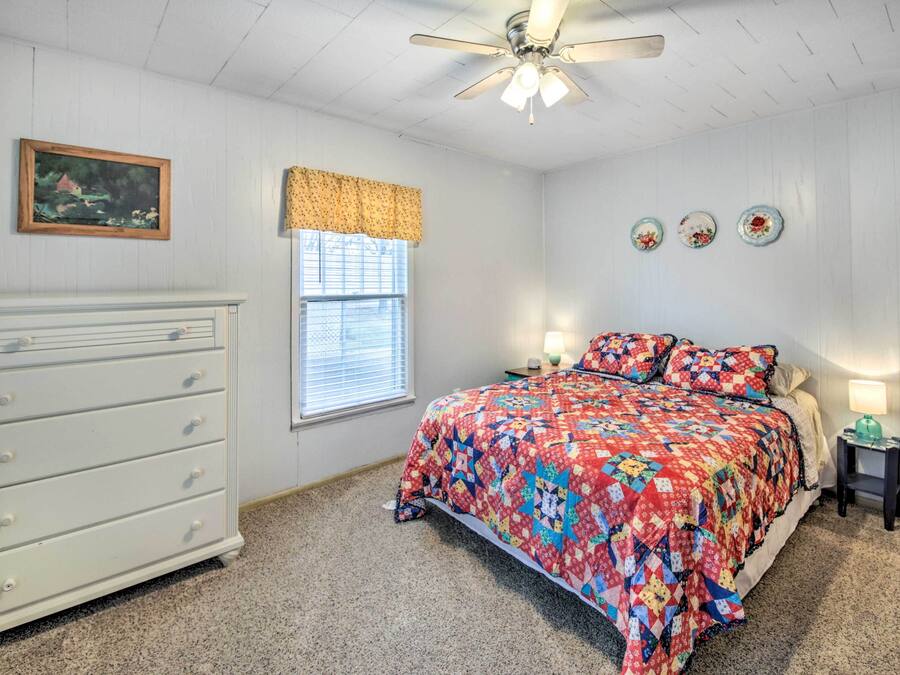 A bedroom with a bed, dresser, window, and ceiling fan.