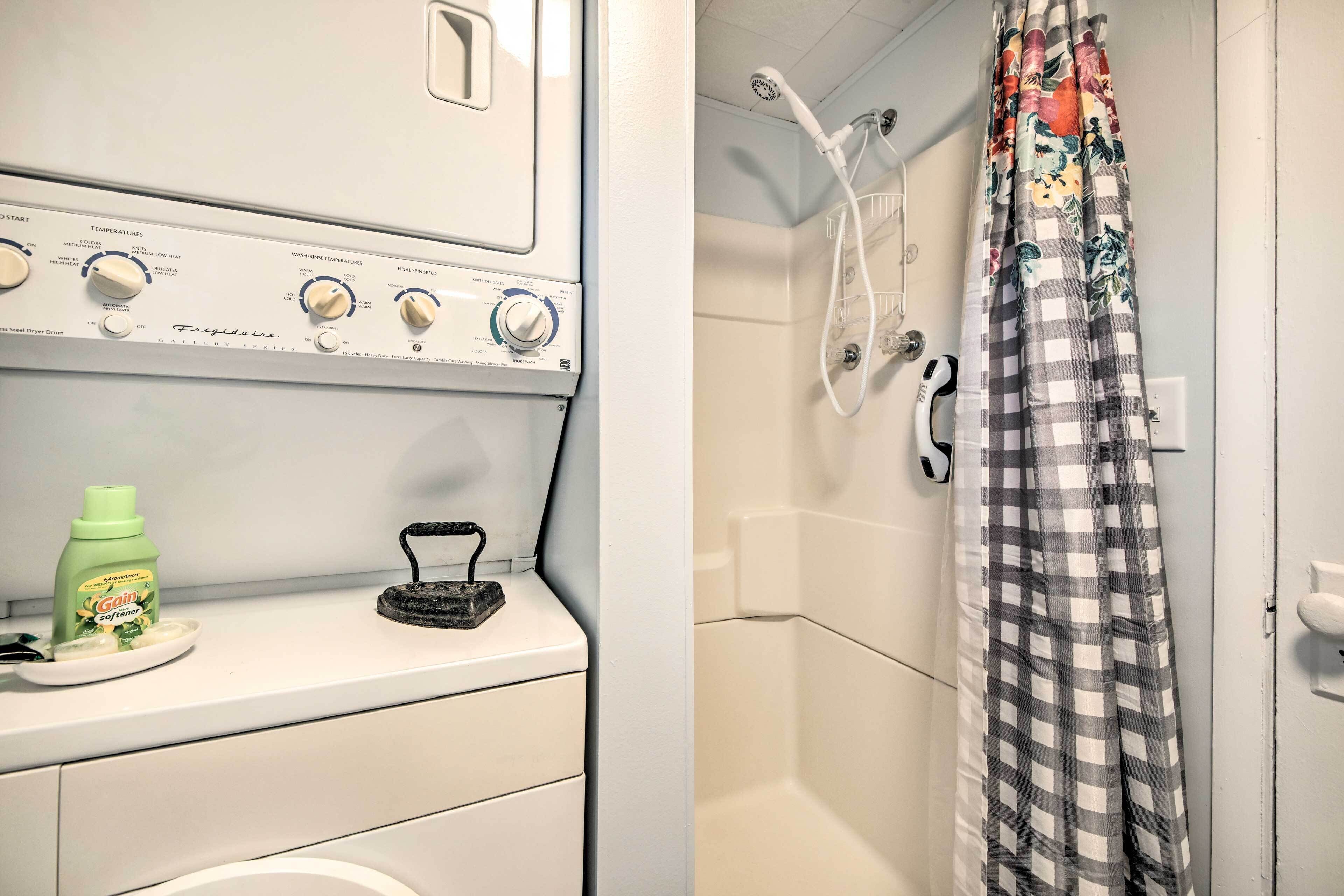 A laundry area with a dryer, a washing machine, and a bottle of Gain detergent.