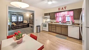 A modern kitchen with wooden cabinets, a white refrigerator, and a microwave. There is a dining area with a table and chairs, and a living room with a couch and a fireplace. - Illinois Vacation Rental Home: Pets Welcome (Palestine)