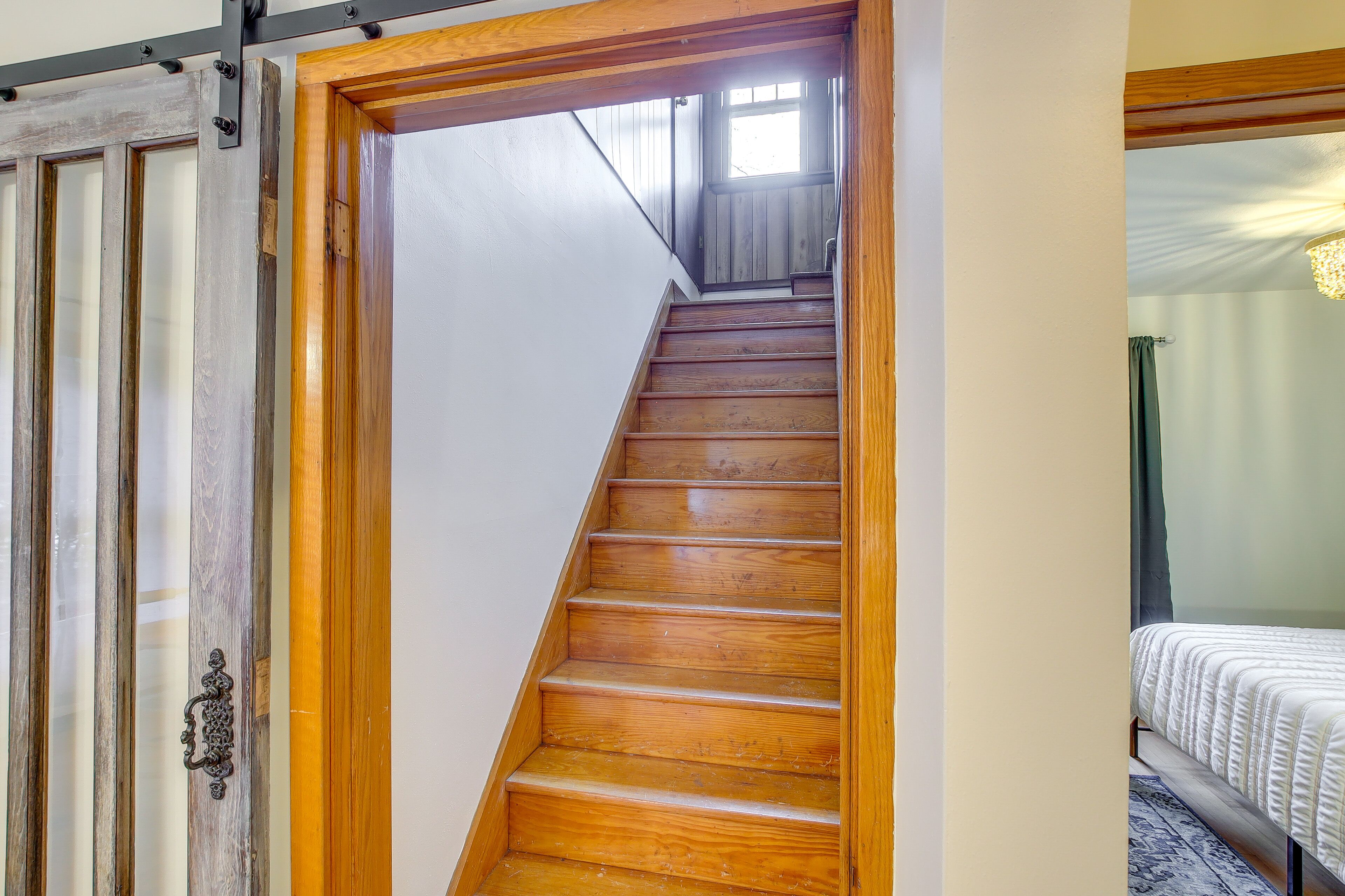 Un escalier en bois mène à une chambre à coucher qui contient un lit et une fenêtre.