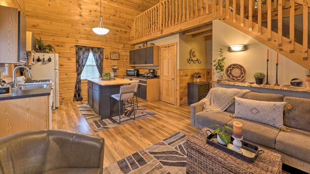 A cozy cabin interior with a wooden interior, a kitchen area, a dining space, and a living room with a sofa and a coffee table.