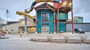 A building with a water slide, an entrance, and a parking area.