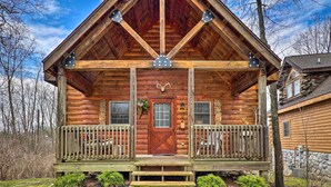 A log cabin with a front porch, a wooden door, and a chimney.