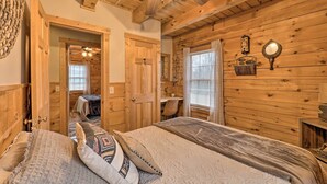 A wooden cabin bedroom with a bed, a desk, and a window.