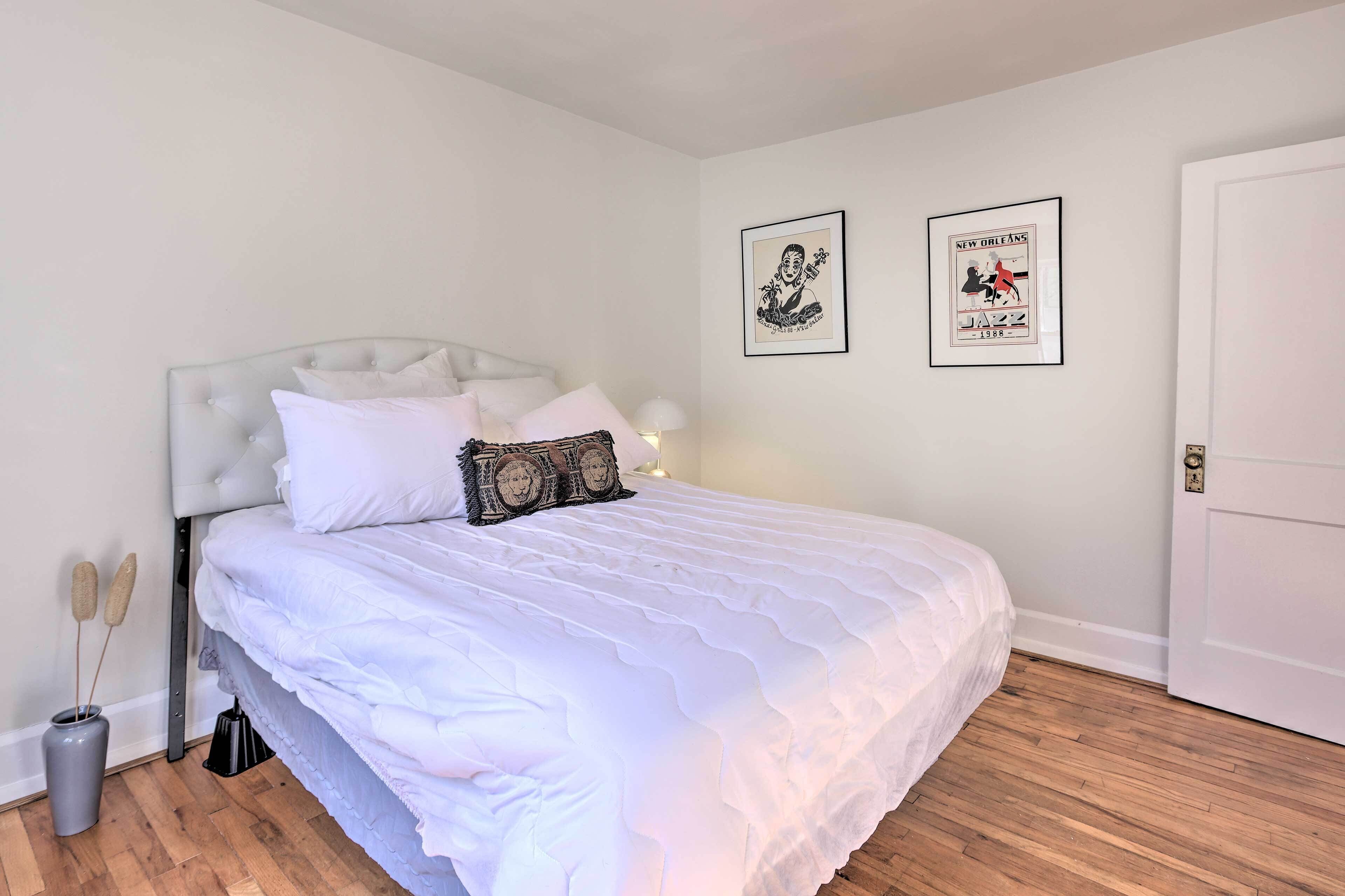A neatly made bed with white bedding, a tufted headboard, and two framed pictures on the wall.