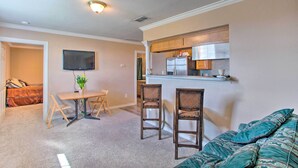 A compact living space with a kitchenette, a dining area with a table and chairs, and a sofa.