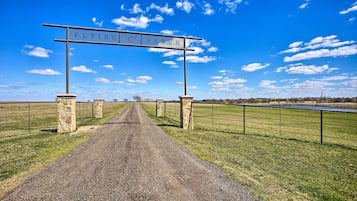Un camino de grava que lleva a un letrero que dice 'FLYING C RANCH'.