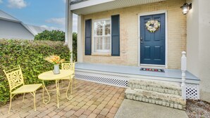 A two-story house with a front porch, a blue door, and a white railing. - Old Town Bay St Louis Townhome: Walk to Beach (Bay St Louis)