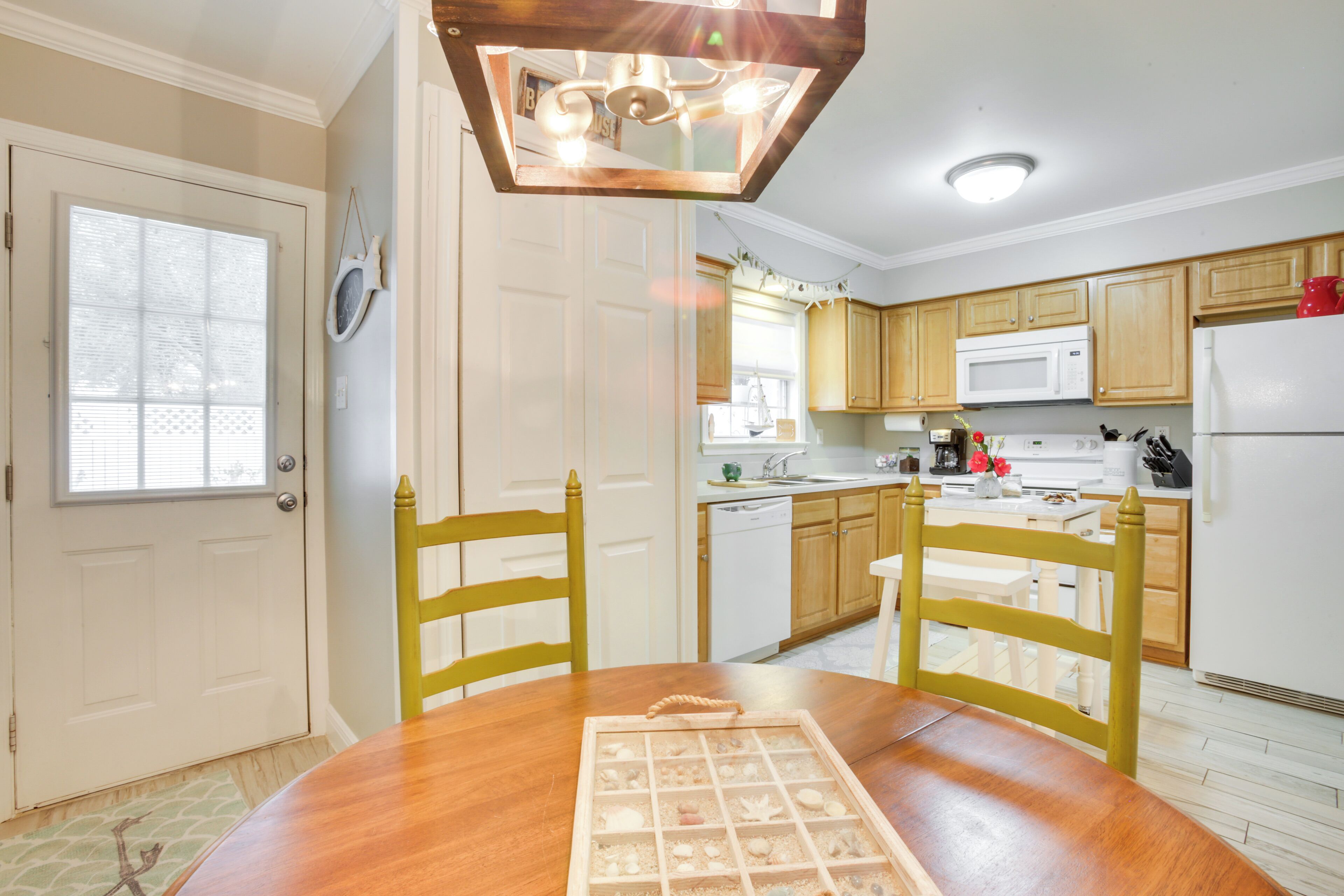 Una cocina con armarios de madera, un refrigerador blanco y una mesa de comedor con sillas.