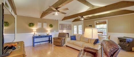A spacious living room with a wooden ceiling, a fireplace, and a television on a wooden cabinet.