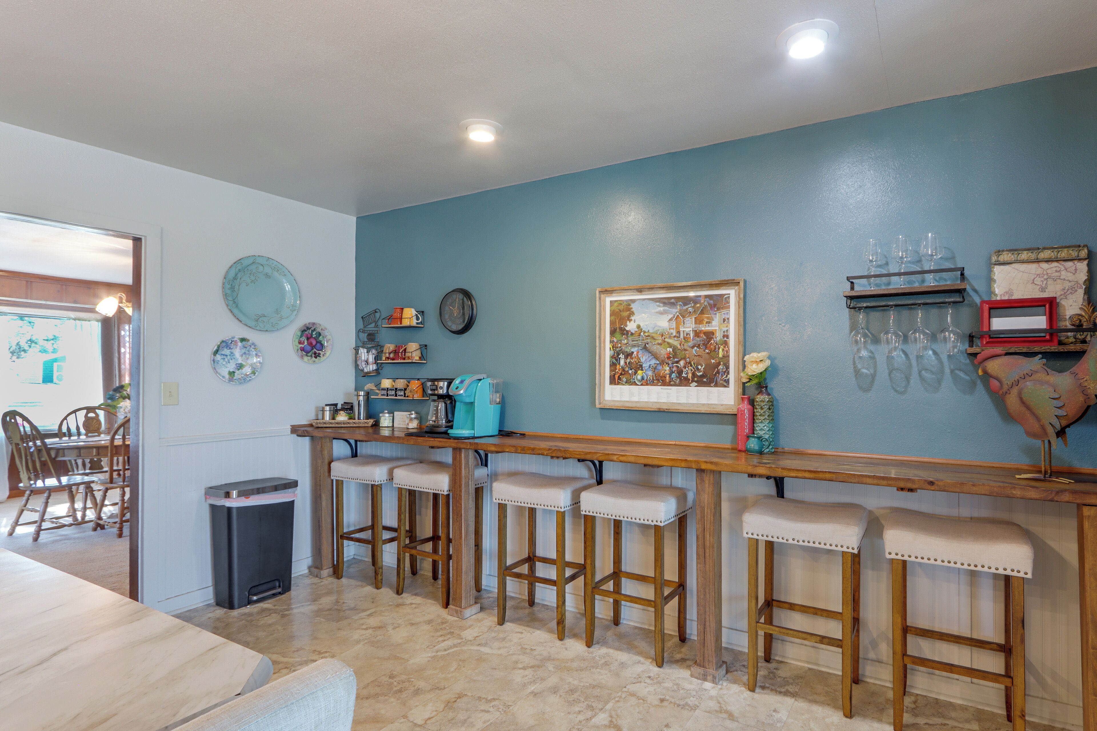 A kitchen with a bar area, stools, a coffee machine, and various kitchenware on the wall.