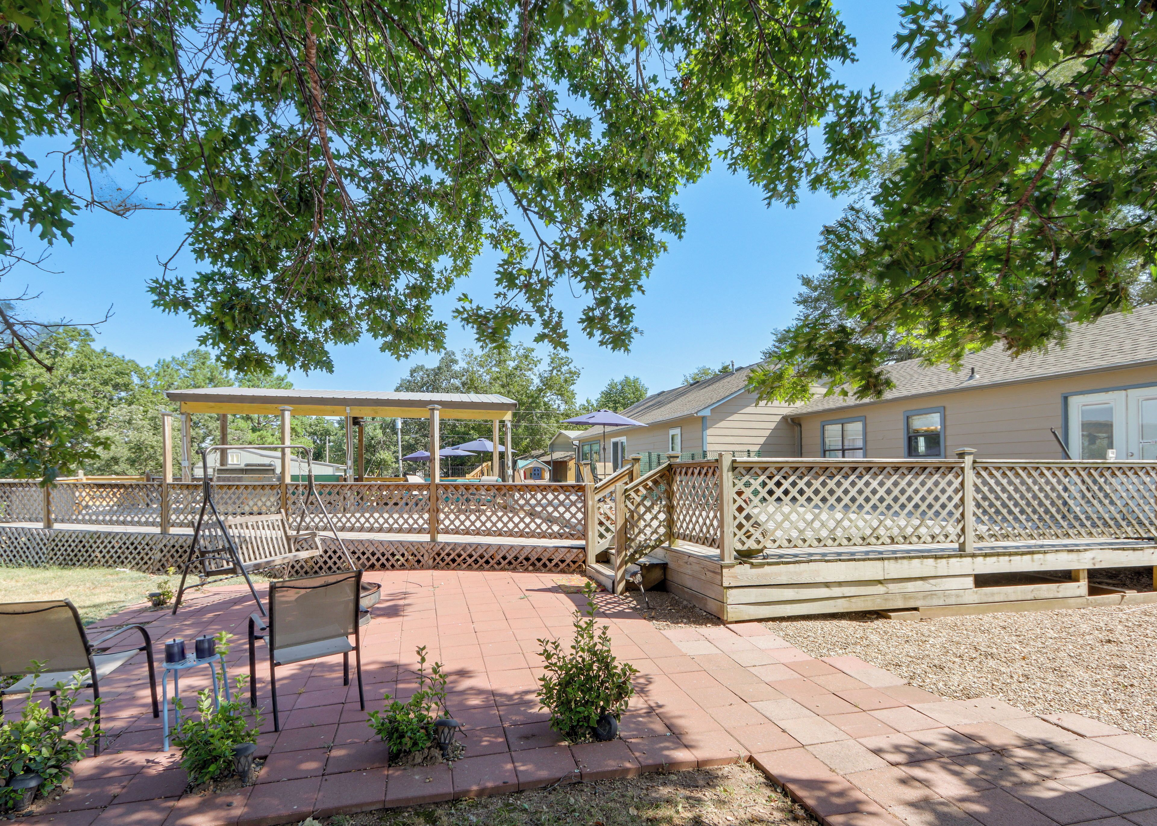 Un patio couvert avec une terrasse en bois, des sièges d’extérieur et un petit jardin.