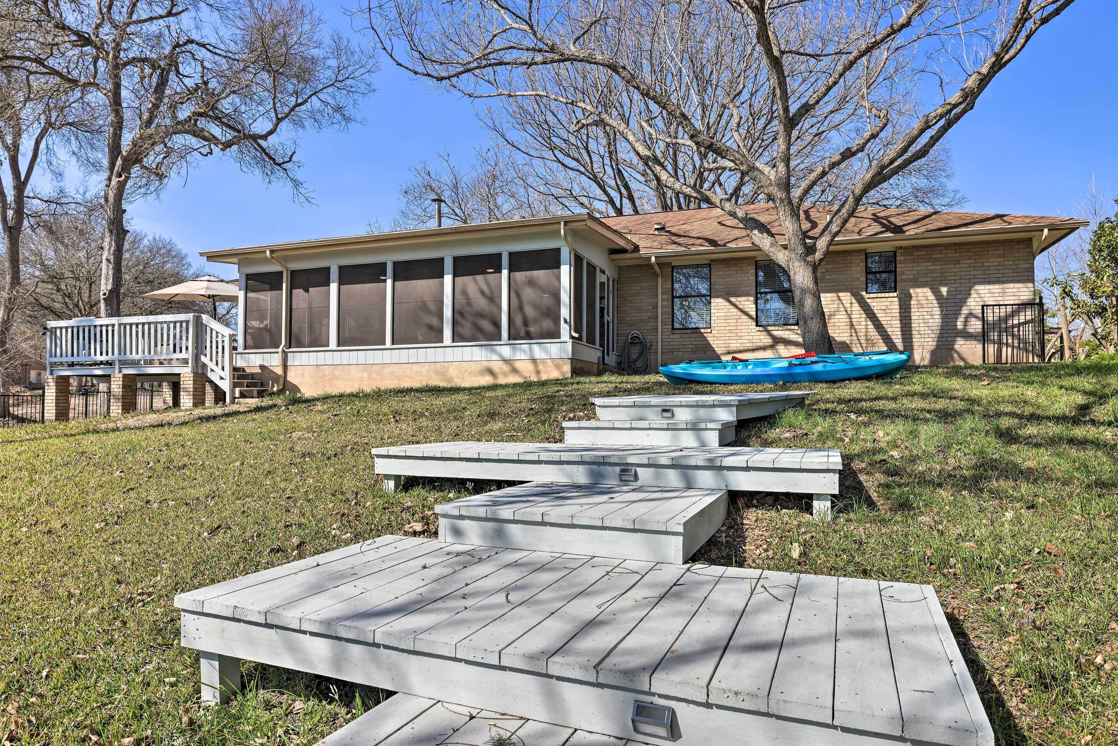 A house with a screened porch, a swimming pool, and a deck with benches.