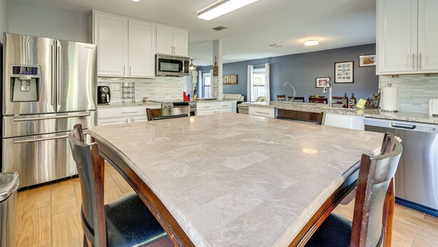 A modern kitchen with stainless steel appliances, white cabinetry, and a large marble island. - New Braunfels Escape, Walk to Gruene Hall! (New Braunfels)