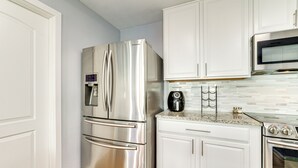 A modern kitchen with white cabinets, stainless steel appliances including a refrigerator and oven, and a tiled backsplash. - New Braunfels Escape, Walk to Gruene Hall! (New Braunfels)