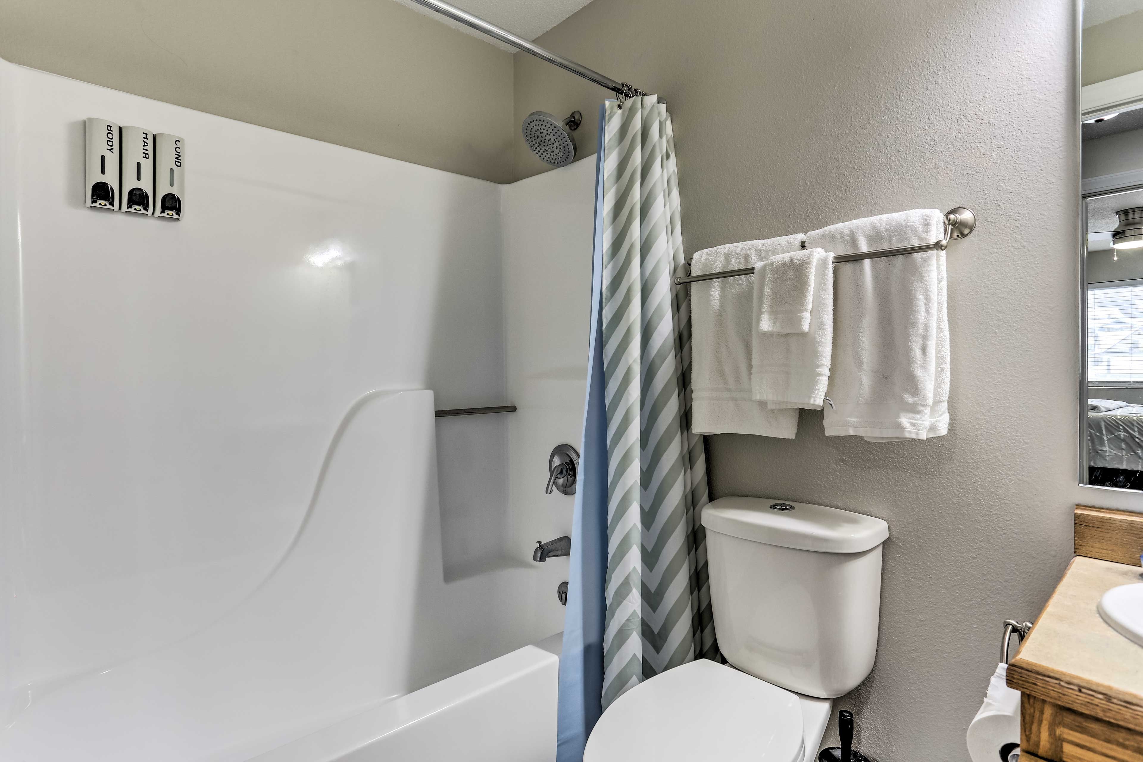 Ein Badezimmer mit Badewanne, Dusche, Toilette und einem Handtuchhalter mit Handtüchern.