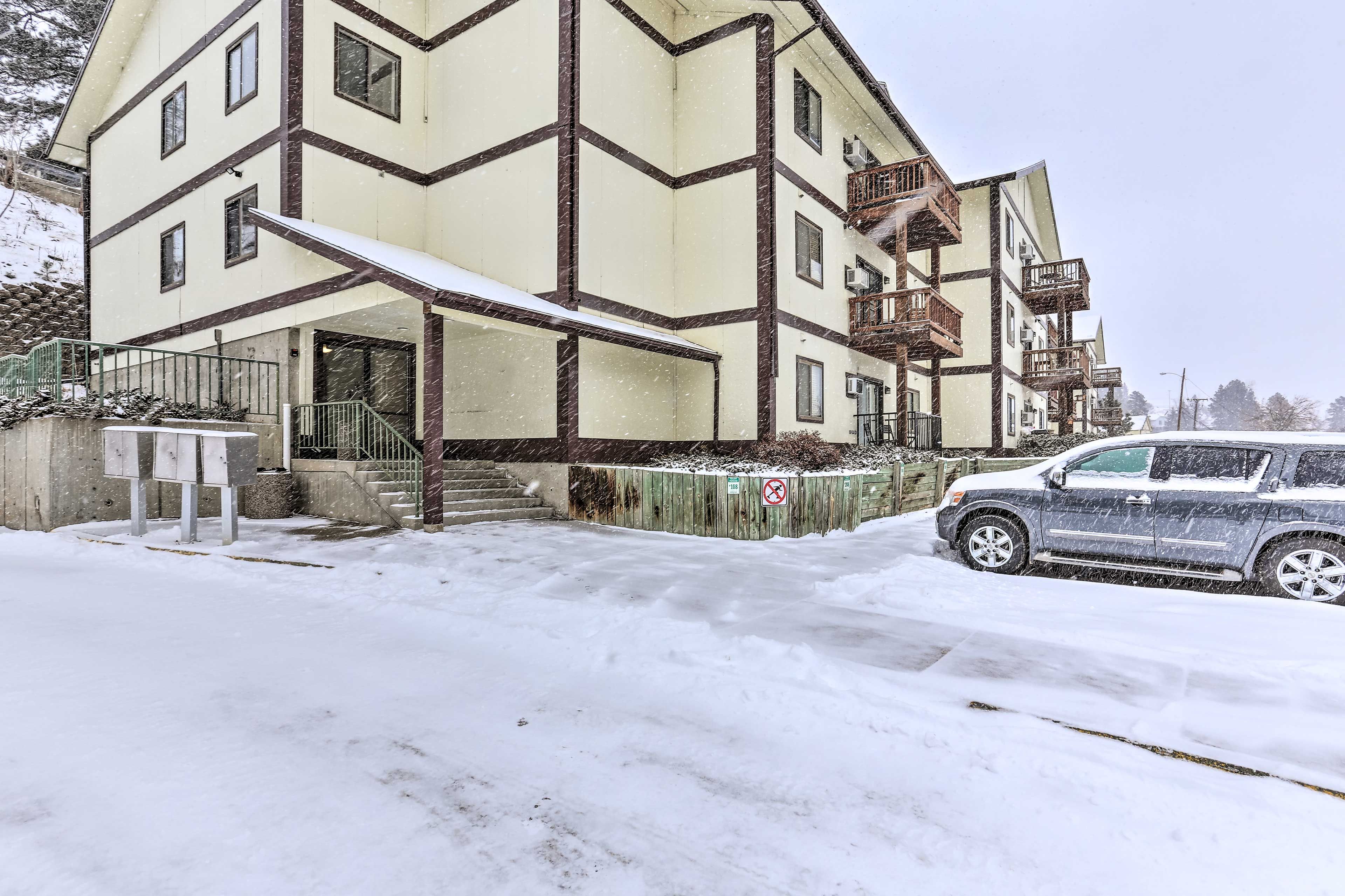 A multi-story building with a snow-covered ground and a parked car.