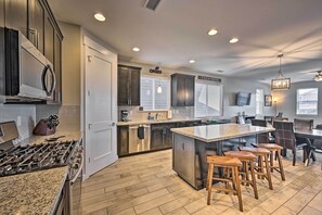 A modern kitchen with granite countertops, stainless steel appliances, and a central island with bar stools.
