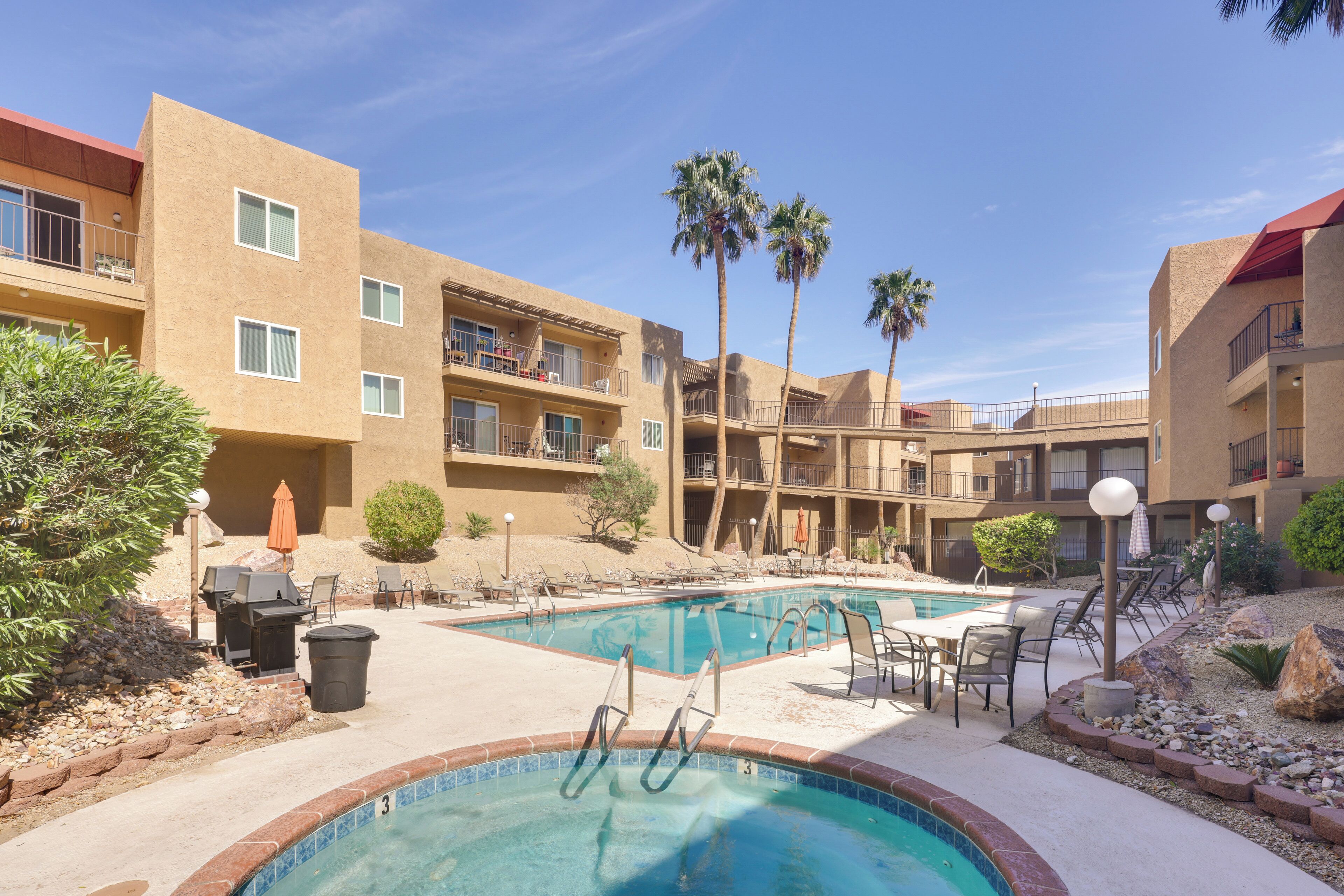 A pool area with lounge chairs, a hot tub, and a small waterfall feature.