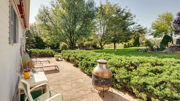 Un patio con una parrilla, mobiliario exterior y un jardín bien cuidado.