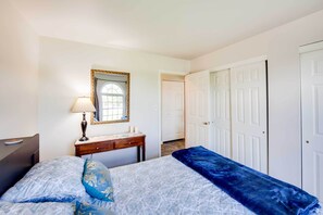 Un dormitorio con cama, mesita de noche con lámpara, espejo y armario.
