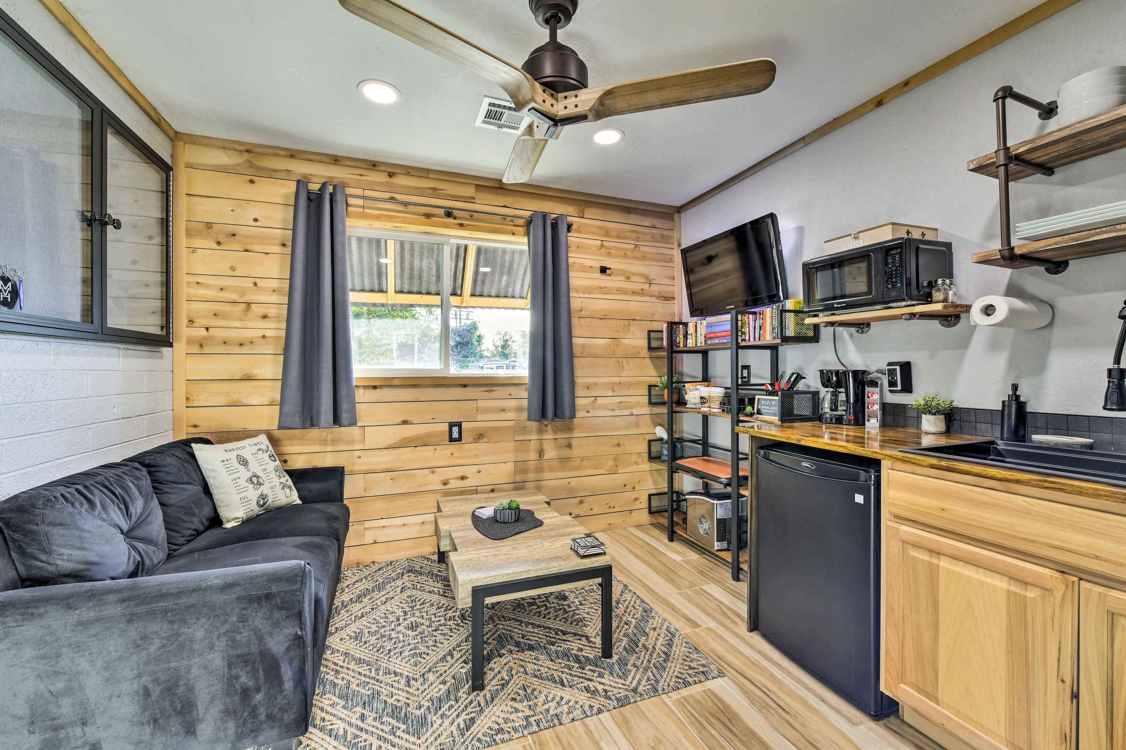 A compact kitchen with a microwave, sink, and wooden cabinets.