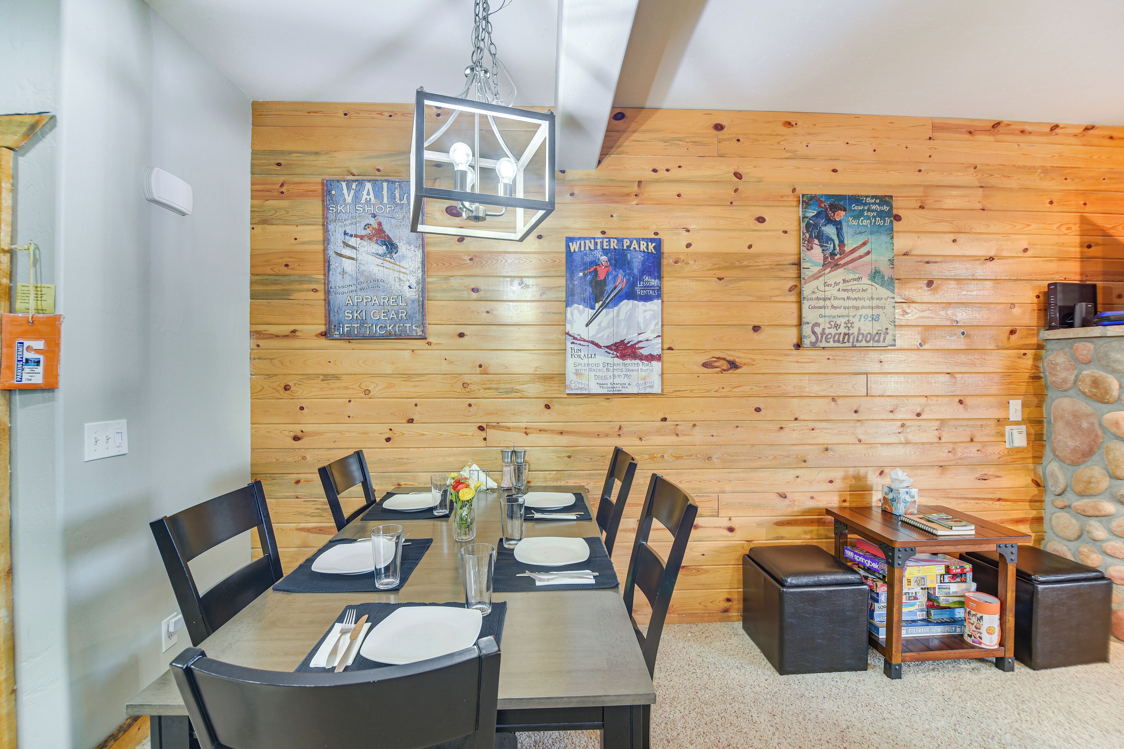 A dining area with a wooden wall, a table set for four, and posters on the wall.