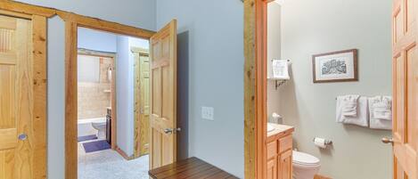 A bathroom with a wooden vanity, toilet, and a small table.