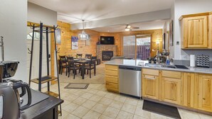 A modern kitchen with wooden cabinets, a dishwasher, and a dining area with a table and chairs. - Patio & Mountain Views: Central Grand Lake Condo! (Grand Lake)