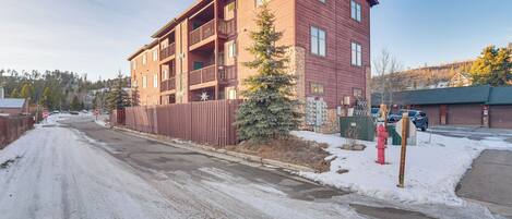 Un edificio de varios pisos con balcones, suelo cubierto de nieve y un hidrante rojo.