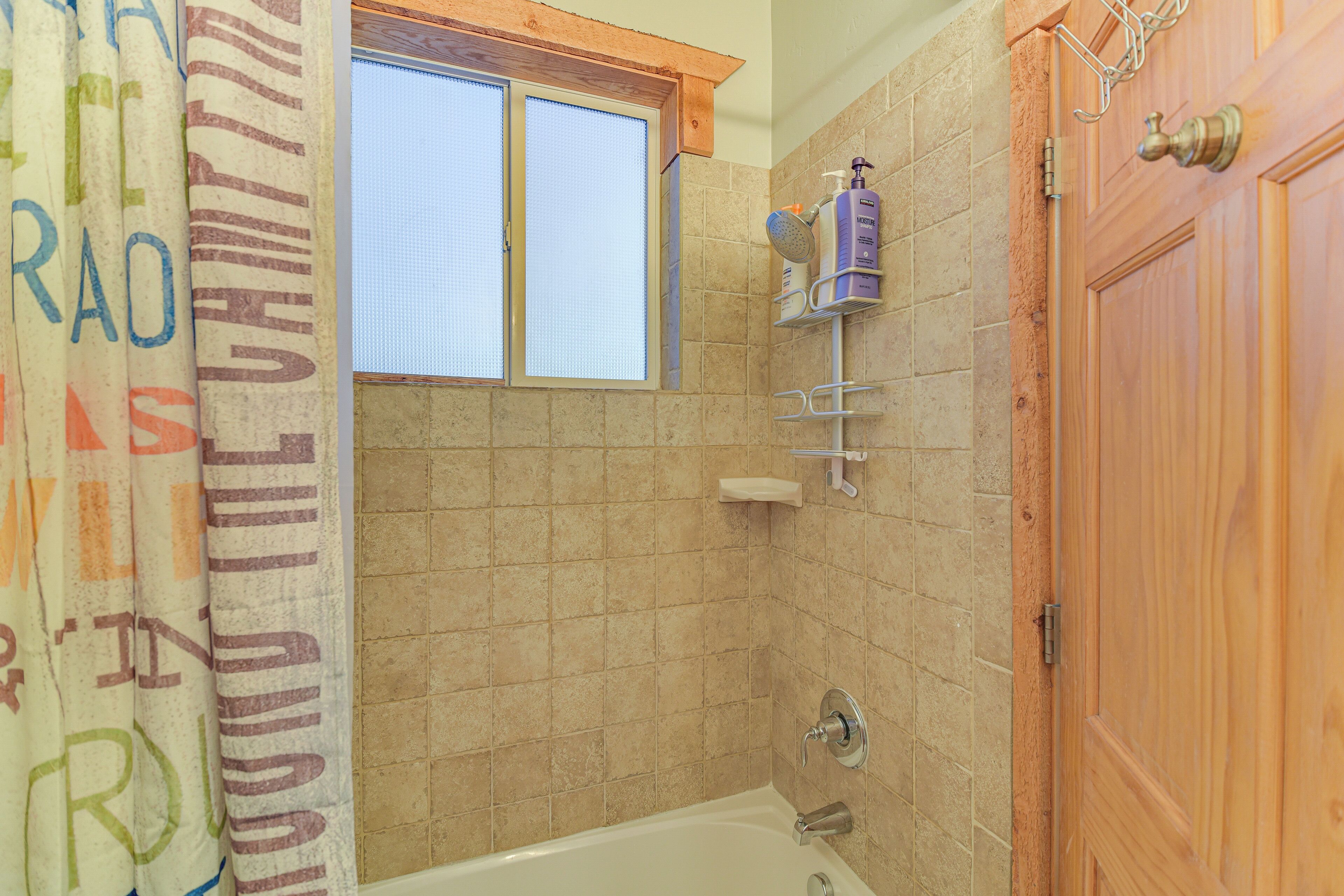 Un baño con bañera, ventana y puerta de madera.