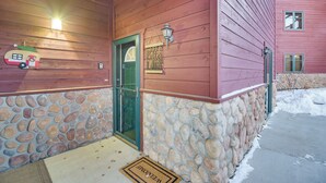 A building with a stone foundation and wooden siding, a green door, and a welcome mat. - Patio & Mountain Views: Central Grand Lake Condo! (Grand Lake)