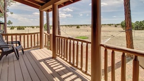 Eine Holzterrasse mit Geländer, einer Bank und Blick auf eine trockene Landschaft mit vereinzelter Vegetation.