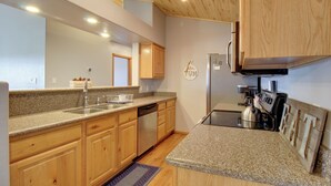 Eine moderne Küche mit Granit-Arbeitsplatten, Holzschränken, einem Geschirrspüler, einem Herd und einem Kühlschrank.