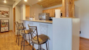 Eine Küche mit Holzausstattung, einem Edelstahlkühlschrank und einer Bar mit Hockern.