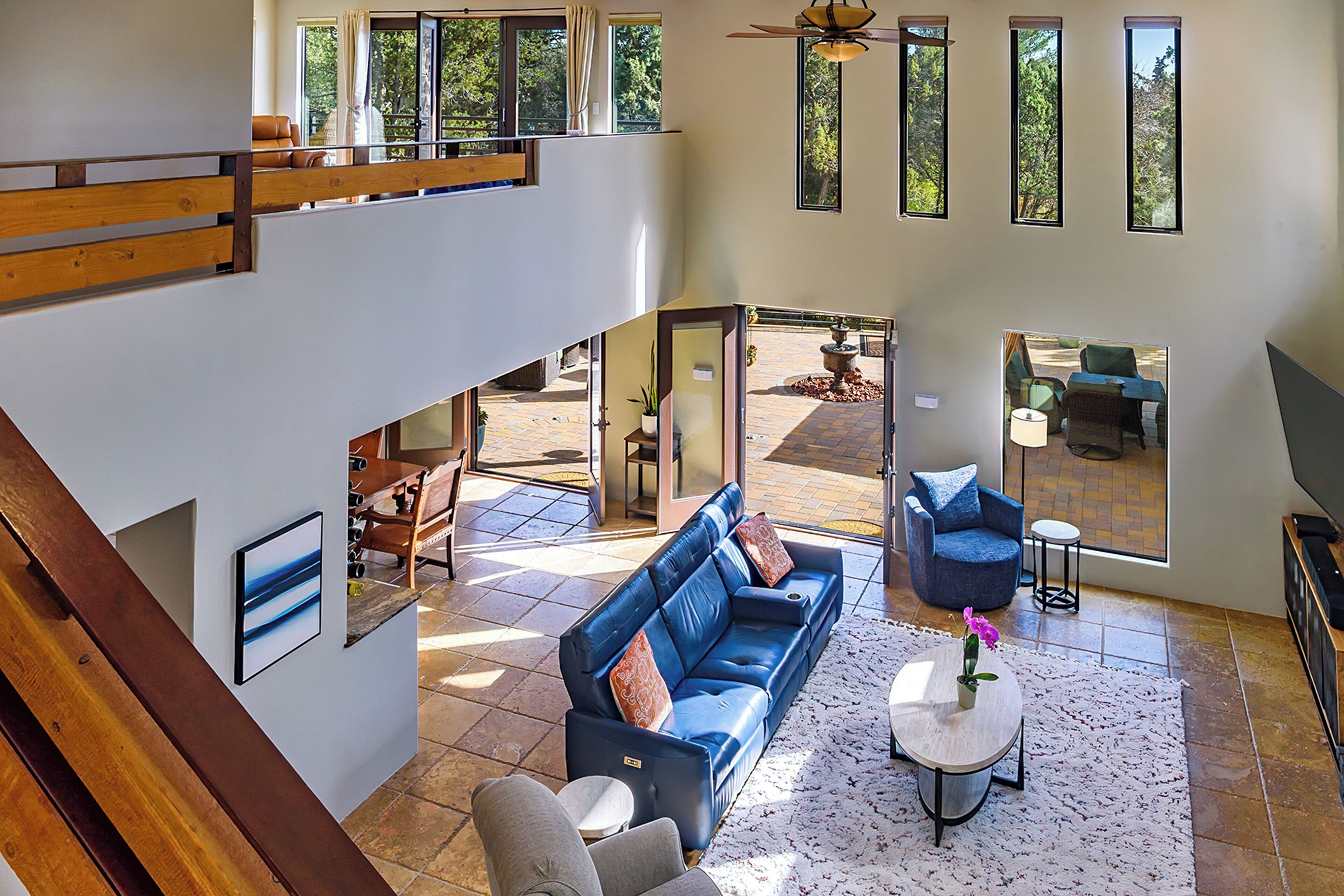 Un amplio espacio de sala con un sofá azul, una mesita de centro y vistas al patio exterior.