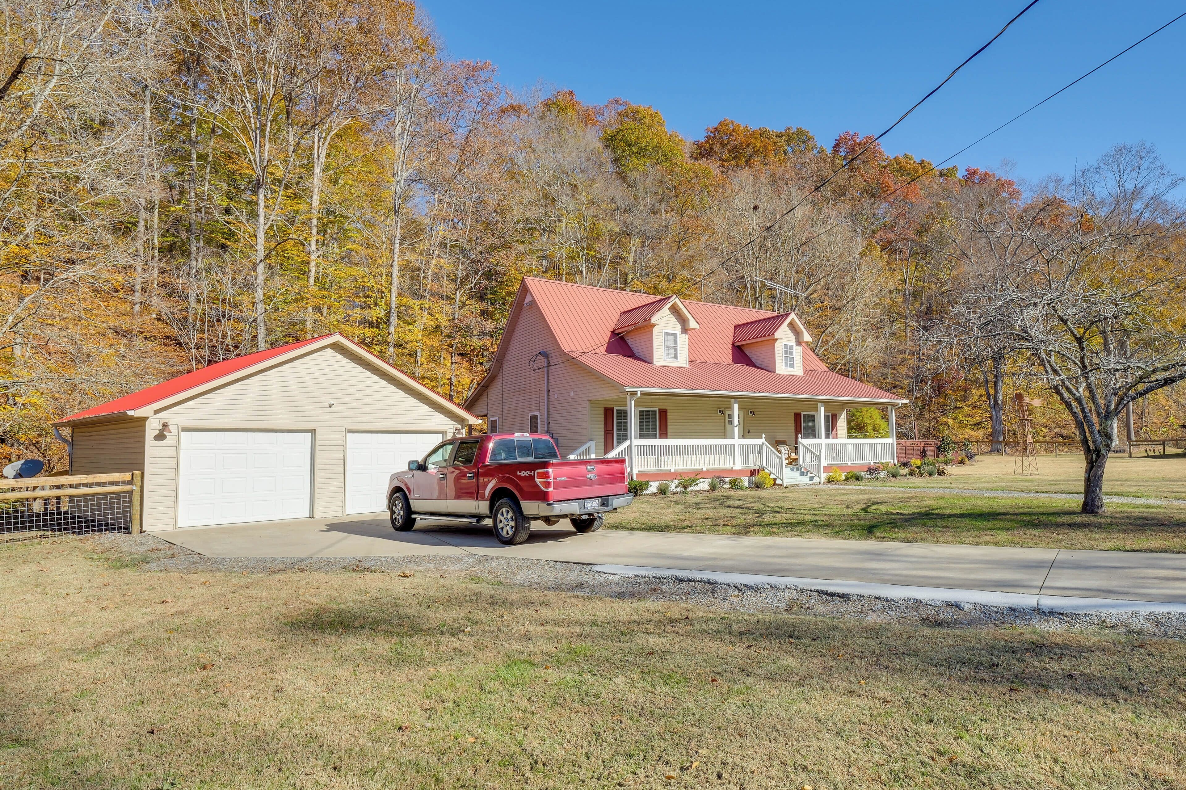 Une maison à deux étages avec un toit rouge, un garage et une véranda couverte.