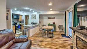 A modern kitchen with a microwave, oven, and sink. There is a dining area with a table and chairs. A brown leather couch is in the foreground. - 1st-floor Wintergreen Resort Condo w/ Balcony (Nellysford)