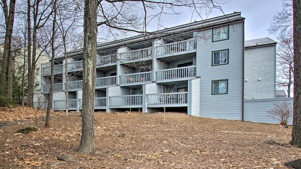 A multi-story building with balconies, surrounded by trees and a leaf-covered ground. - 1st-floor Wintergreen Resort Condo w/ Balcony (Nellysford)