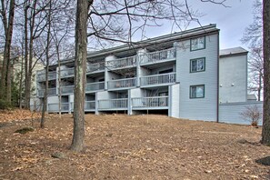 A multi-story building with balconies, surrounded by trees and a leaf-covered ground. - 1st-floor Wintergreen Resort Condo w/ Balcony (Nellysford)