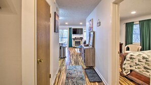 A hallway leading to a bedroom with a bed, a chair, and a fireplace. - 1st-floor Wintergreen Resort Condo w/ Balcony (Nellysford)