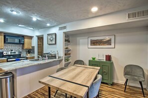 A modern kitchen with a wooden island, built-in appliances, and a dining area with a table and chairs. - 1st-floor Wintergreen Resort Condo w/ Balcony (Nellysford)