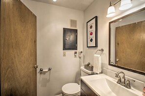 A bathroom with a white sink, a mirror, a towel rack, and a toilet. - 1st-floor Wintergreen Resort Condo w/ Balcony (Nellysford)